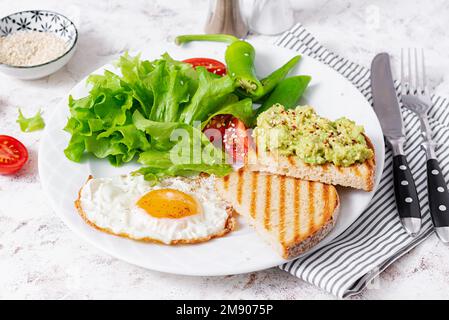 Uova fritte, insalata fresca e panini con guacamole all'avocado. Concetto di uno stile di vita sano Foto Stock