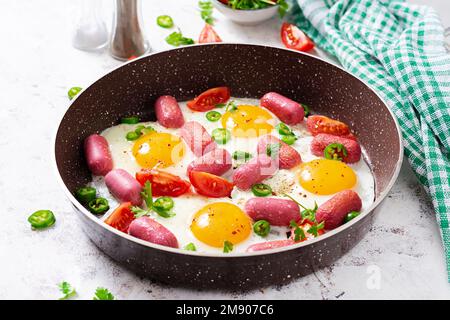 Deliziosa colazione americana fatta in casa con uova fritte, salsicce e pomodori. Concetto di uno stile di vita sano Foto Stock
