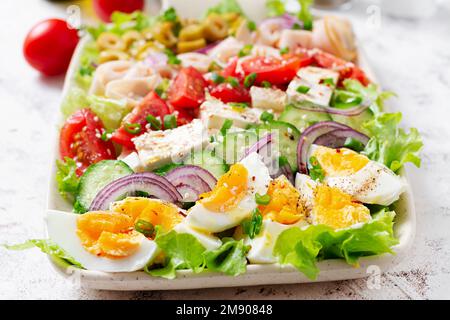 Insalata sana di cobb con prosciutto, cetriolo, pomodoro, olive, formaggio feta e uova. Pranzo chetogenico. Foto Stock