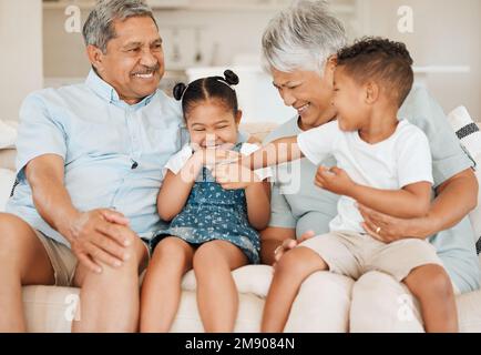 Le famiglie sono come il fudge principalmente dolce con alcuni dadi. nonni che si legano con i loro nipoti su un divano a casa. Foto Stock