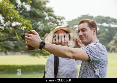 felice giovane sorridente coppia selfie con smartphone in viaggio estivo in vacanza. uomo e donna coppia amante prendere autoritratto con la natura all'aperto p Foto Stock