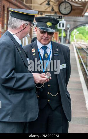 Un stationmaster della stazione ferroviaria di Toddington nei Cotswolds in Gran Bretagna mostra la guardia del treno il vecchio orologio della vita di suo nonno quando era statio Foto Stock