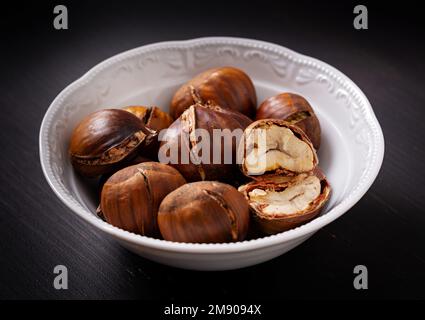 Castagne arrosto su fondo di legno scuro Foto Stock