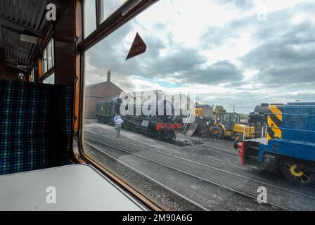 Da una finestra di una carrozza a vapore per passeggeri d'epoca della stazione ferroviaria di Toddington di un vicino cantiere di smistamento di locomotive o di marshalling nel Co Foto Stock