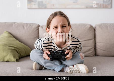 KIEV, UCRAINA - 28 NOVEMBRE 2022: Bambino tensed che tiene il joystick mentre gioca il video gioco Foto Stock