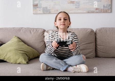 KIEV, UCRAINA - 28 NOVEMBRE 2022: Ragazza allegra che tiene il joystick durante il gioco video Foto Stock