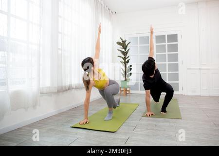 Giovane uomo e donna che pratica yoga e stretching muscolo mani e schiena per la salute insieme sul tappetino in camera a casa, coppia allenamento yoga Foto Stock