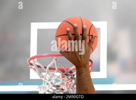 Corto di mano nera di un giocatore di basket maschio in azione contro allo stadio Foto Stock
