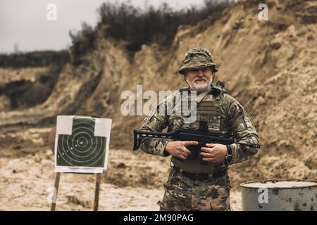 Soldato maturo con un fucile in mano su un campo di tiro Foto Stock