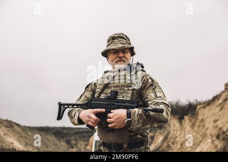 Soldato maturo con un fucile in mano su un campo di tiro Foto Stock