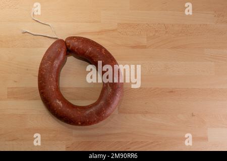 Vista dall'alto della tradizionale salsiccia circolare fermentata su sfondo di legno con area di testo. Foto Stock