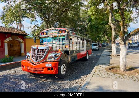 Autobus di pollo colorato che corre sulla strada principale di Antigua Guatemala. Trasporto pubblico tipico per turisti e locali. Foto Stock