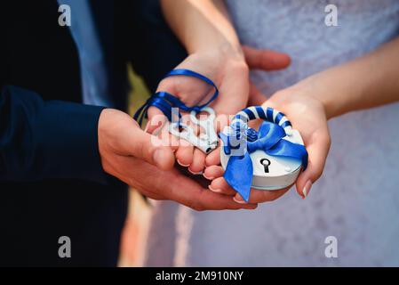 sposa e sposo tenere un lucchetto e chiavi. Tradizione di matrimonio russo per consolidare il rapporto per l'eternità Foto Stock