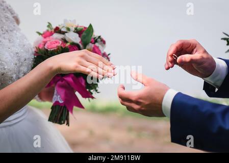 lo sposo mette sul closeup dell'anello d'oro di nozze della sposa della mano Foto Stock