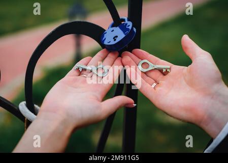 sposa e sposo tenere le chiavi del lucchetto. Tradizione di matrimonio russo per consolidare il rapporto per l'eternità Foto Stock