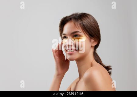 Emotivo giovane bella ragazza con ben tenuto pelle fare viso procedure cosmetologia isolato su sfondo chiaro. Bellezza, arte, emozioni, spa Foto Stock