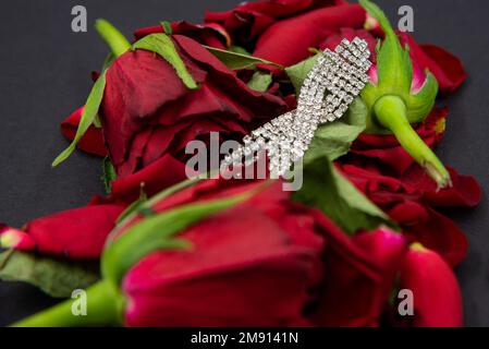 Ornamento di diamante femminile in fiori di rosa rossi su sfondo nero. Foto Stock