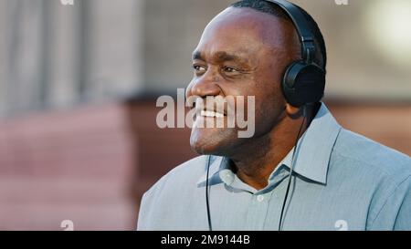 Primo piano overjoyed uomo afroamericano anziano indossando cuffie divertirsi ascoltando musica in movimento rilassarsi felice maturo di mezza età pensionato etnia maschio Foto Stock