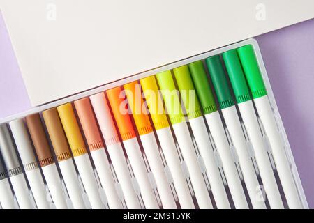 Set di marcatori luminosi di acquerello per gli schizzi e un foglio di schizzo disposto su una tabella. Disegno e arte tema hobby. Copia spazio per il testo Foto Stock