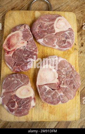 fette crude di ossobuco su un tagliere di legno Foto Stock