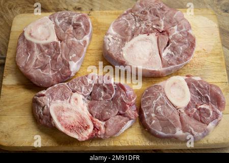 fette crude di ossobuco su un tagliere di legno Foto Stock