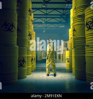 uomo in tuta di protezione gialla in magazzino con fusti metallici con residui radioattivi e chimici. Foto Stock
