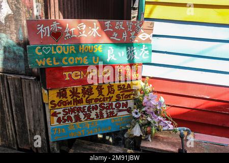 Georgetown, Penang, Malesia - Novembre 2012: Indicazioni su una colorata tavola di legno che indica varie attrazioni turistiche come la Colour House e. Foto Stock