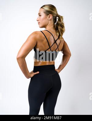 Brawny bella giovane donna che indossa Ponytail mostrando muscoli posteriori Foto Stock