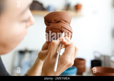 Le mani femminili tengono una ciotola per la colata di prodotti di argilla. Metodo sagomato per fare piatti di creta. Lavoro manuale. Ceramica fare. Foto Stock