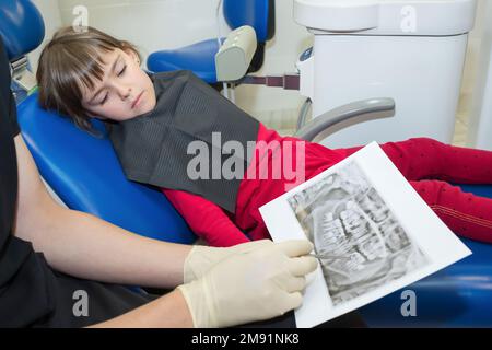 Un dentista e un paziente bambino stanno guardando ai raggi X dentali Foto Stock