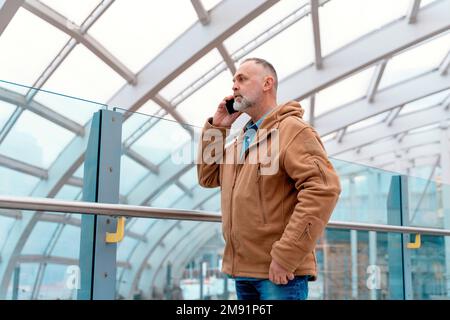 Ritratto all'aperto di un uomo infelice che parla al telefono in una città urbana in Inghilterra Foto Stock