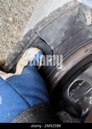 Meccanico manuale maschio POV che mostra pneumatici danneggiati dopo un incidente Foto Stock