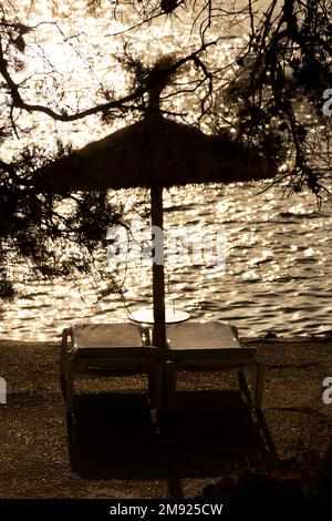 Illetes, Mallorca, Spagna. 20 luglio 2022 - Vista della luce sul mare dietro un ombrellone e lettini nella baia di Comtesa Foto Stock