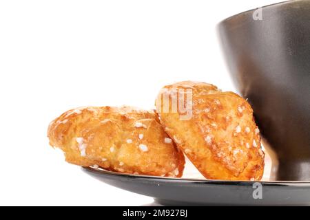 Due chouquette dolci con una tazza su un piatto, primo piano, isolato su bianco. Foto Stock