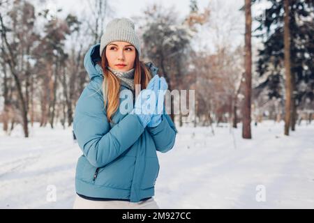 Ritratto di giovane donna che cammina nel parco invernale innevato indossando un cappotto blu. Abiti caldi per climi freddi. Spazio Foto Stock