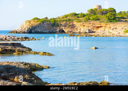 Costa rocciosa della baia di Xinxell, a Ses Illetes a Maiorca, sullo sfondo l'isola di SA torre con la sua torre Foto Stock