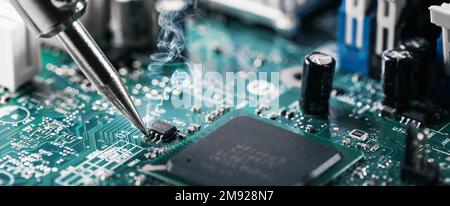 saldatore saldare il chip del computer sulla scheda a circuito stampato. banner con spazio di copia Foto Stock