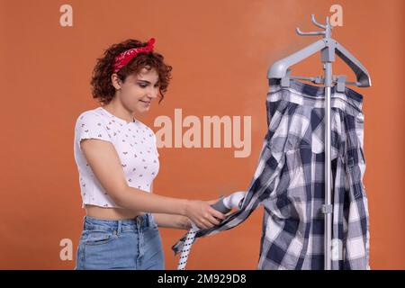 Una donna con un sorriso sul viso ferra la camicia di un uomo con un vaporizzatore. Foto Stock