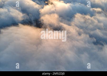 Vista aerea dall'alto ad alta quota di dense nuvole di cumulo puffy volare in serata. Incredibile tramonto dal punto di vista della finestra dell'aeroplano Foto Stock