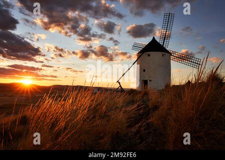 Tramonto a Molino Sancho - Tramonto a Molino Sancho uno dei 12 mulini a vento di Consuegra che coronano la collina, con erba in primo piano illuminata Foto Stock