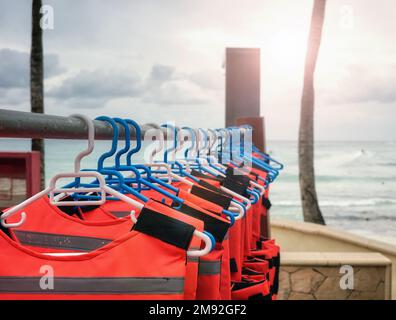 Giubbotti di salvataggio asciugati su grucce in spiaggia, fuoco selettivo. Foto Stock