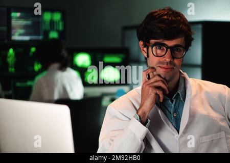 Primo piano ritratto di attraente medico con occhiali e camice da laboratorio guardando la fotocamera. Vista frontale di bella farmacia scientifica con occhiali che lavorano sullo spazio scientifico. Concetto di sanità e medicina. Foto di alta qualità Foto Stock