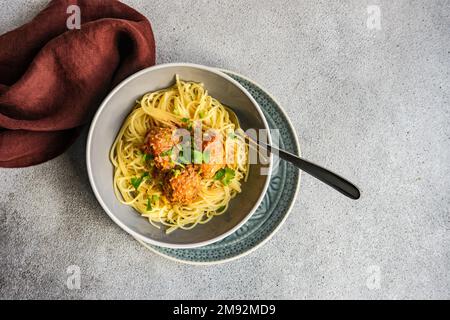 Da sopra ciotola con pasta e polpette su fondo tavolo in cemento Foto Stock