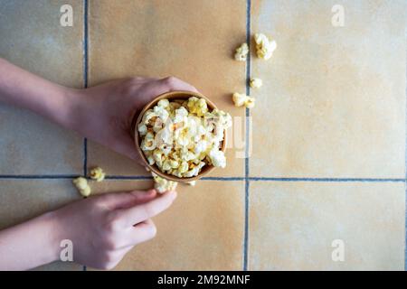 Tazza di carta con spuntino di popcorn sul tavolo piastrellato Foto Stock