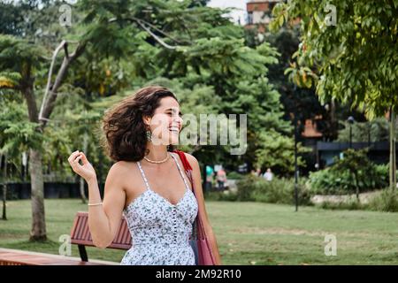 Felice giovane donna in estate vestito ridendo mentre godendo di una giornata di sole nel parco Foto Stock