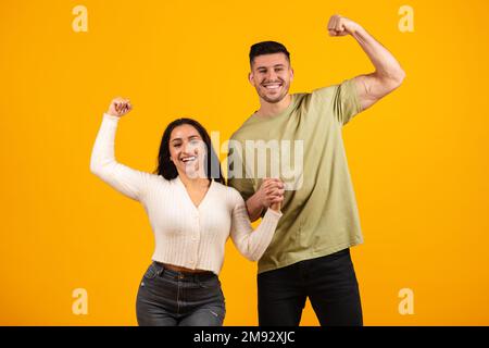 Sorridente marito e moglie arabo millenario tenendo le mani, mostra bicipiti a portata di mano Foto Stock