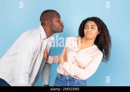 Concetto di Friendzone. Giovane donna nera disgustata evitando bacio indesiderato da parte di un uomo di mezza età Foto Stock