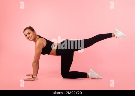 Ritratto di giovane donna sportiva fare gamba sollevamento esercizio in Studio Foto Stock