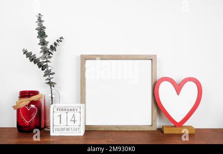 Struttura in legno con decorazioni e calendario a cuore di San Valentino. Mensola di legno contro una parete bianca. Spazio di copia. Foto Stock