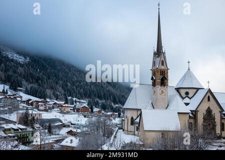 Moena, Dolomiti, Italia, gennaio 16th 2023. Parrocchia di San Vigilio con cottage e chalet coperti di neve fresca Foto Stock